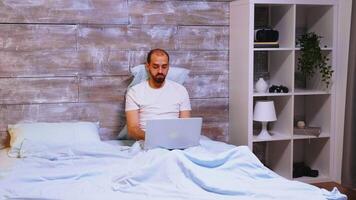 freelancer werken laat Bij nacht Aan laptop houdende in bed vervelend pyjama. video