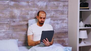 Man using tablet computer before going to sleep. Checking social media. video