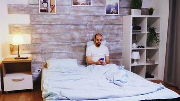 Man scrolling on social media using smartphone before going to sleep. video