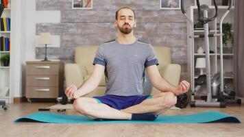 Man in lotus position on yoga mat focusing in slow breathing. video