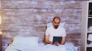 Man in pajamas surfing on tablet computer before bedtime video