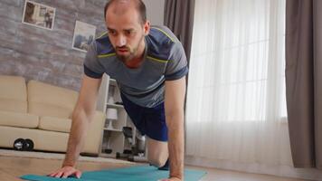 Athletic guy doing mountain climbers training on yoga mat at home wearing sportswear. video