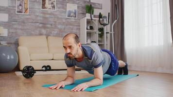 Fit man in sportswear doing plank workout on yoga mat at home. video