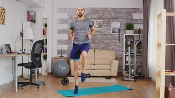 Athletic guy doing cardio workout running on spot in living room wearing sportswear. video