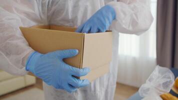 Close up of volunteer packing food in box wearing protective suit against covid-19. video