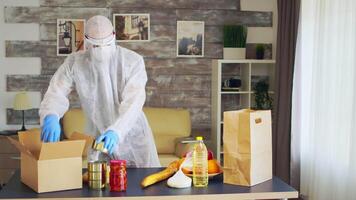 hombre en materiales peligrosos traje embalaje comida durante coronavirus brote. video
