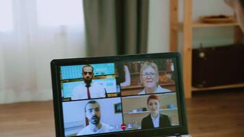 Zoom out shot of man on a video call with his work team during covid-19 lockdown.