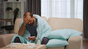 Sad and sick man on sofa wrapped with blanket during global pandemic. video