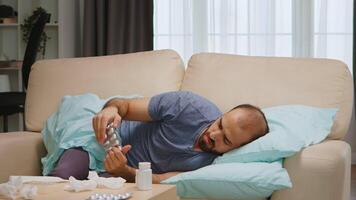 Sick man lying on sofa covered with blanket during global pandemic. video