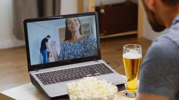 gelukkig het beste vriend Aan video telefoontje gedurende covid quarantaine. Mens Holding een glas van bier.