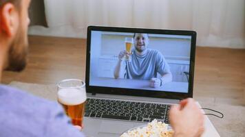 Mens golvend Bij zijn vriend gedurende een video telefoontje in timp van covid-19 en bier Aan de tafel.