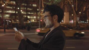 Young Asian Man With Glasses Using Tablet Screen Computer in the City at Night video