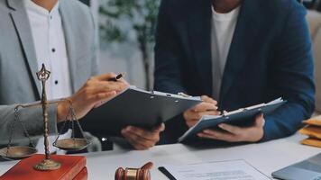 Justice and Law concept. Legal counsel presents to the client a signed contract with gavel and legal law or legal having team meeting at law firm in background video