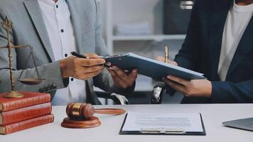 Justice and Law concept. Legal counsel presents to the client a signed contract with gavel and legal law or legal having team meeting at law firm in background video