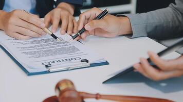 Justice and Law concept. Legal counsel presents to the client a signed contract with gavel and legal law or legal having team meeting at law firm in background video