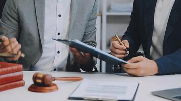 Justice and Law concept. Legal counsel presents to the client a signed contract with gavel and legal law or legal having team meeting at law firm in background video