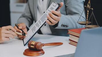 Justice and Law concept. Legal counsel presents to the client a signed contract with gavel and legal law or legal having team meeting at law firm in background video