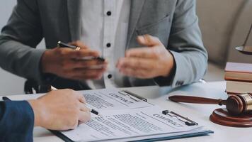 Justice and Law concept. Legal counsel presents to the client a signed contract with gavel and legal law or legal having team meeting at law firm in background video