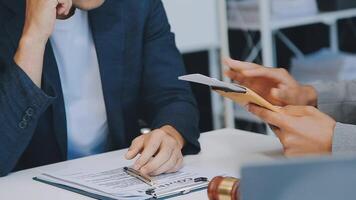 Justice and Law concept. Legal counsel presents to the client a signed contract with gavel and legal law or legal having team meeting at law firm in background video