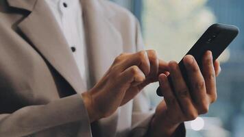 Smiling businesswoman using phone in office. Small business entrepreneur looking at her mobile phone and smiling. video