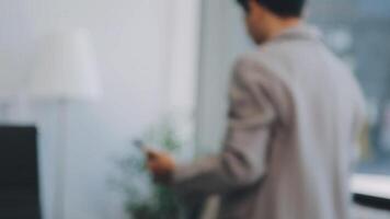 Smiling businesswoman using phone in office. Small business entrepreneur looking at her mobile phone and smiling. video