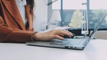 Closeup image of a business woman's hands working and typing on laptop keyboard on glass table video