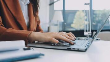 Closeup image of a business woman's hands working and typing on laptop keyboard on glass table video