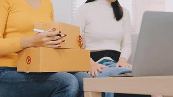 Shipping shopping online ,young start up small business owner writing address on cardboard box at workplace.small business entrepreneur SME or freelance asian woman working with box at home video