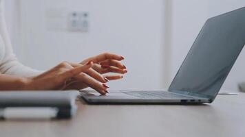 Closeup image of a business woman's hands working and typing on laptop keyboard on glass table video