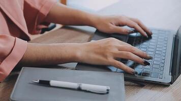 avvicinamento Immagine di un' attività commerciale donna di mani Lavorando e digitando su il computer portatile tastiera su bicchiere tavolo video