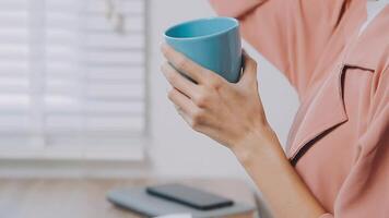 charmant vrouw met mooi glimlach lezing mooi zo nieuws Aan mobiel telefoon gedurende rust uit in koffie winkel, gelukkig Kaukasisch vrouw aan het kijken haar foto's Aan cel telefoon terwijl ontspannende in cafe gedurende vrij tijd video