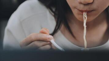 Close up Asian woman eating yummy hot and spicy instant noodle using chopsticks and bowl. Eating on the table video