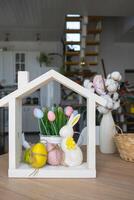 Tiny house of cozy home with Easter decor with rabbit and eggs on table of kitchen. Building, design, project, moving to new house, mortgage, insurance, rent and purchase real estate photo