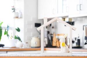 Tiny house of cozy home with Easter decor with rabbit and eggs on table of kitchen. Building, design, project, moving to new house, mortgage, insurance, rent and purchase real estate photo