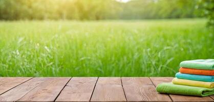 AI Generated Cleaning cloth towel on wooden table. Green field and sky backdrop. Products for eco-friendly cleaning. photo