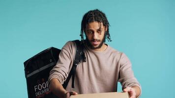 Portrait of BIPOC courier delivering pizza order to client. Delivery part time worker using thermal backpack to store food and bring it to customer, isolated over studio background, camera A video