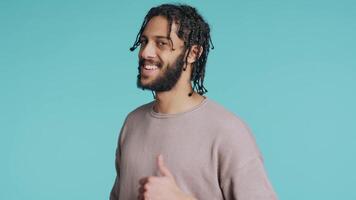 Man doing thumbs up hand gesturing, showing approval, having positive mood. Cheerful BIPOC person presenting confirmation, doing agreement finger sign, studio background, camera B video