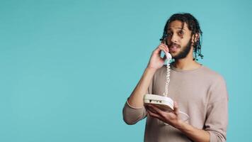 middle eastern happy man chatting with best friend over telephone call. Upbeat person communicating with mate using landline phone, isolated over studio background, camera A video