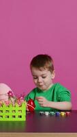 Ecstatic little kid using watercolor and paintbrushes to decorate eggs and create festive baskets as festive arrangements. Happy child enjoys painting and coloring decorations for easter. Camera B. video