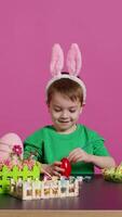 Smiling jolly preschooler painting eggs and ornaments for easter festivity preparations, using art and craft materials to decorate festive arrangements. Young boy having fun with tie dye. Camera B. video