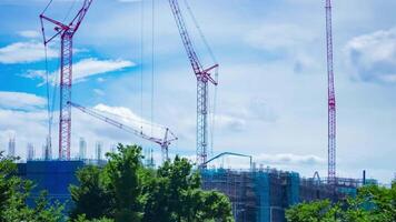 une laps de temps de en mouvement grues à le en dessous de construction jour inclinaison video