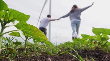 Couple runs holding hands against the background of wind turbines video