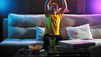 Boy plays a video game console and dances with joy