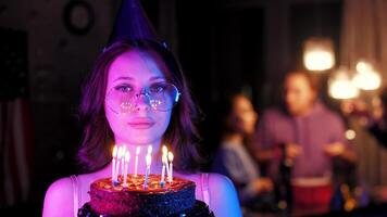 A young birthday girl holds a cake with burning candles in her hands video