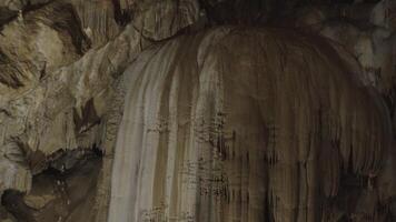 A girl takes pictures of stalagmites on the wall in a cave on her phone video