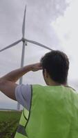 un ingénieur inspecte une vent turbine dans le champ. video