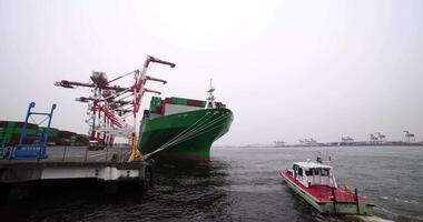 A large ship near the container wharf in Tokyo cloudy day wide shot video