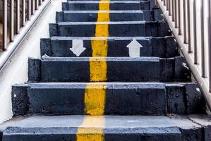 línea amarilla y flecha de dirección pintadas en la escalera de hormigón del paso elevado foto