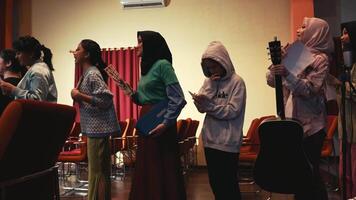 Diverse group of women standing in a row during a gathering or event, some holding books and a guitar. video