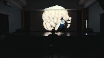 Silhouette of a person on stage with dramatic lighting and a projected brain illustration in the background. video